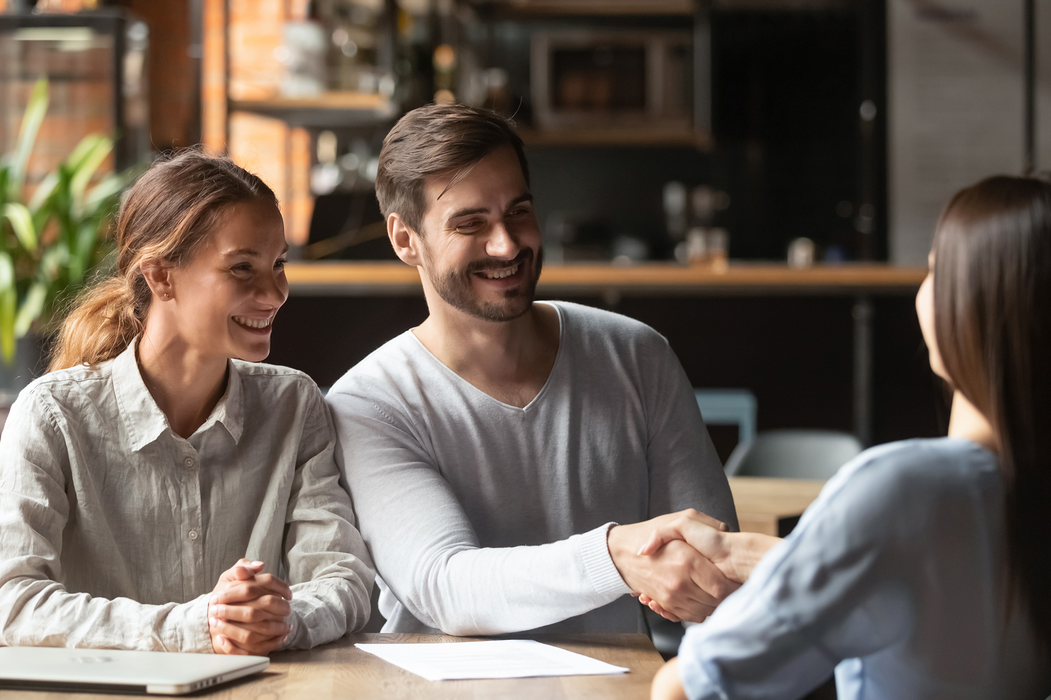 Woman and man sitting in a office shaking hands with a mortgage broker.